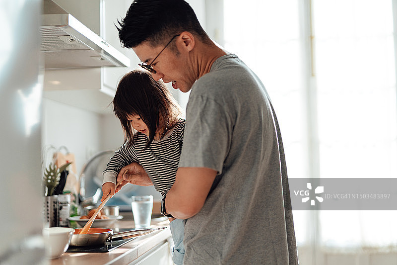 年轻的亚洲父亲和女儿在家里的厨房一起做饭图片素材