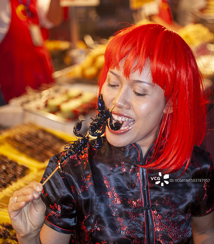 在北京食品市场吃蝎子串的女人图片素材