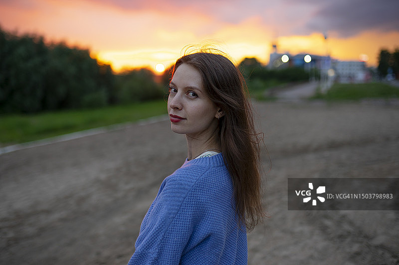 美丽女人在日落时分站在田野里的肖像图片素材