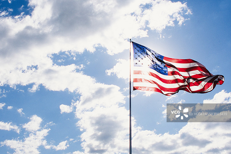 阳光明媚的天空下飘扬的美国国旗图片素材