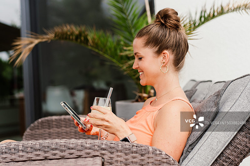 在日光浴床上放松并使用手机的妇女图片素材