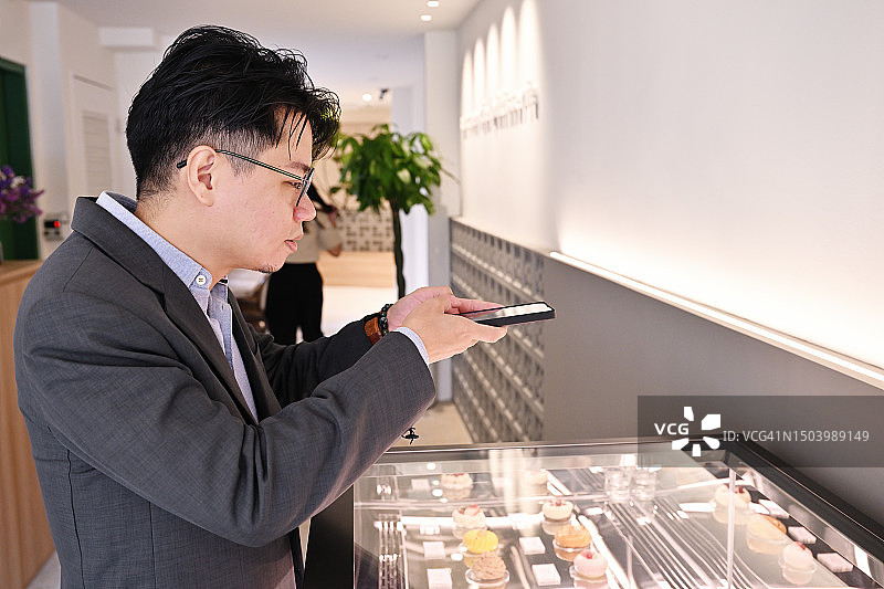 男子拍摄糕点展示柜图片素材