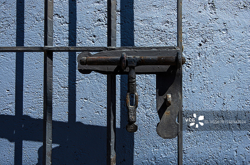 灰蓝色粉刷建筑外墙上的旧铁安全门和门栓图片素材