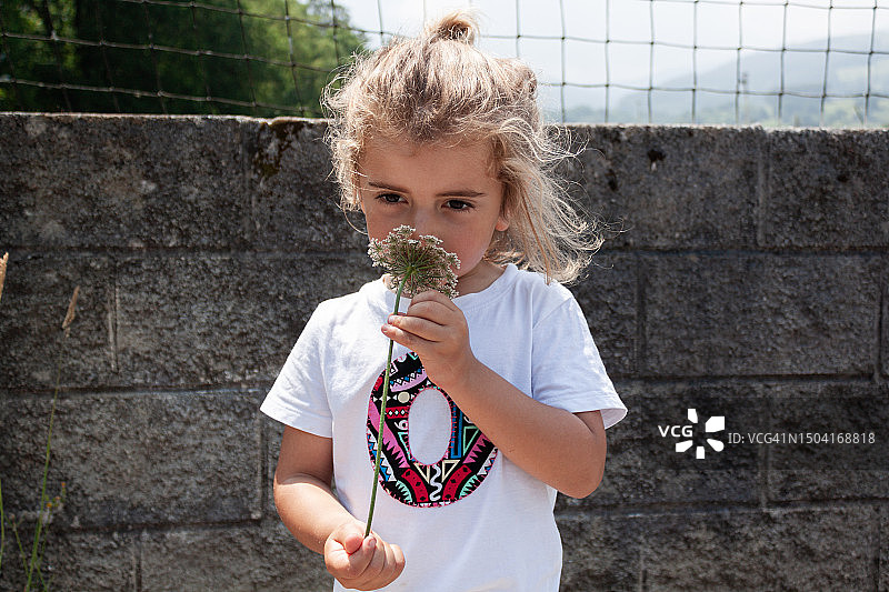 金发可爱小男孩正在闻花香图片素材