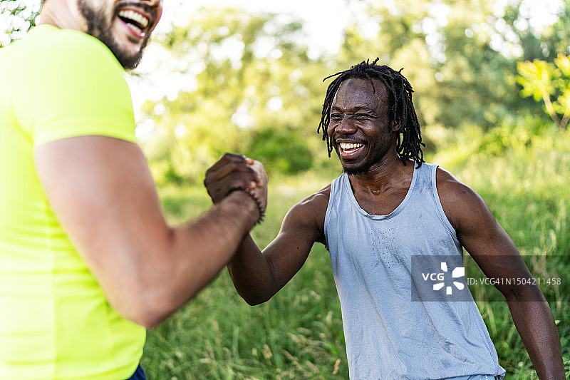 两位慢跑者在夏季户外锻炼时互相击掌问候图片素材