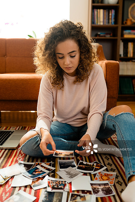 年轻女摄影师正在看打印在纸上的一些照片图片素材