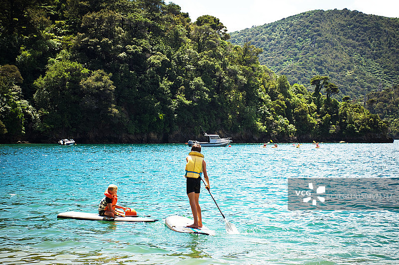 男孩们在海上玩桨板图片素材