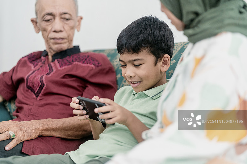 祖父母与小男孩一起玩智能手机图片素材