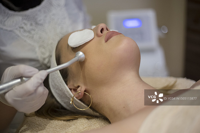 美容师为年轻女子进行面部微晶磨皮护理图片素材