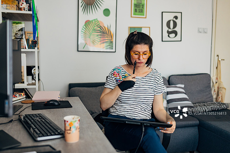 女网络插画师在家工作，坐在电脑前的办公椅上绘制插图图片素材
