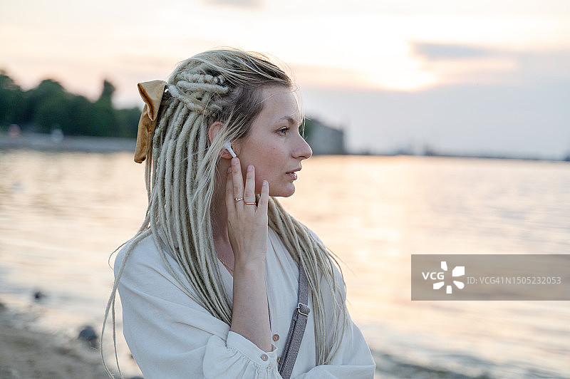 有脏辫的女人在海边听音乐图片素材