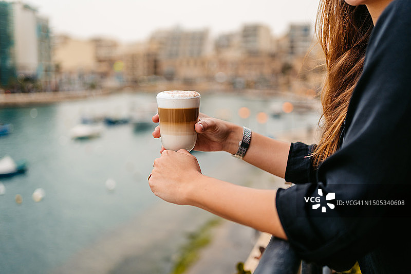 年轻女人在马耳他圣朱利安湾咖啡馆露台上喝咖啡图片素材