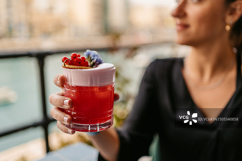 年轻女人在马耳他圣朱利安湾的酒吧露台上喝水果鸡尾酒图片素材