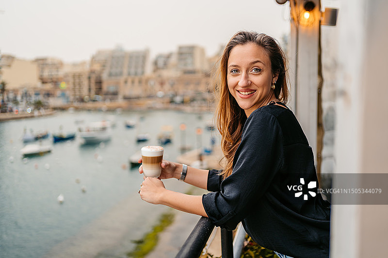 年轻女人在马耳他圣朱利安湾咖啡馆露台上喝咖啡图片素材