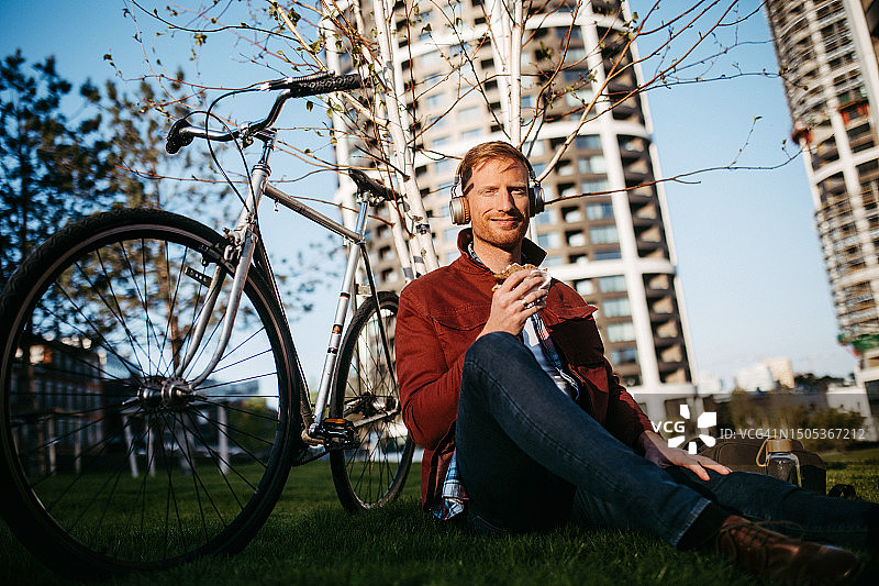 快乐的男人带着自行车在城市公园休息，通勤概念图片素材