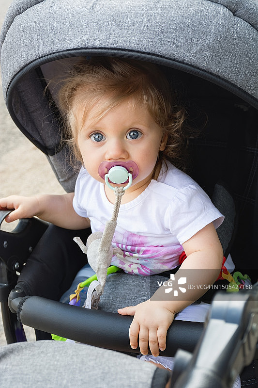 小女孩叼奶嘴坐婴儿车或和妈妈散步图片素材