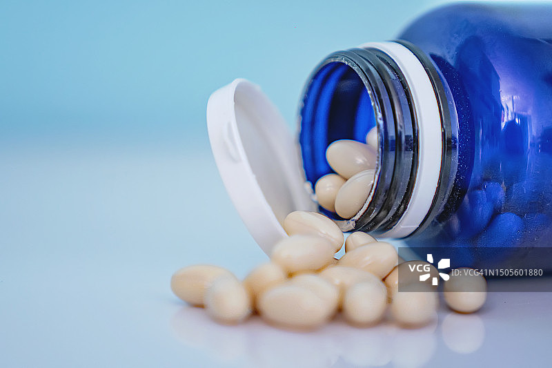 蓝色药瓶中倾泻而出的白色胶囊图片素材