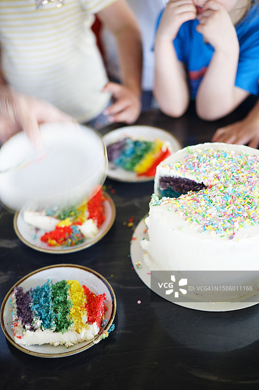 孩子们等待分发生日蛋糕，彩虹蛋糕和香草奶油，庆祝新鲜烘焙的蛋糕图片素材