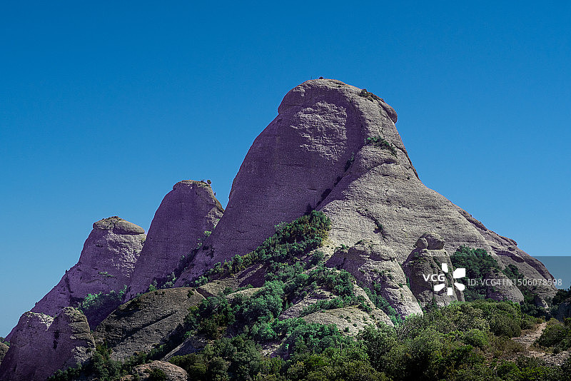 仰视：西班牙蒙特塞拉特的岩层与晴朗的蓝天图片素材