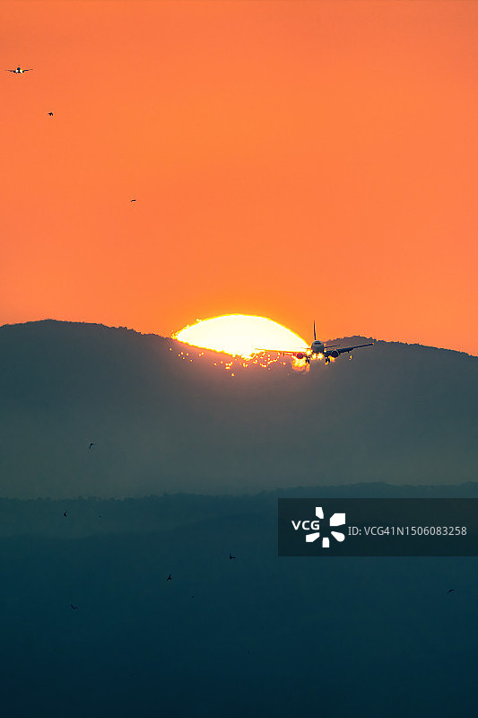 飞机降落时飞过太阳，划出壮观的火焰轨迹图片素材