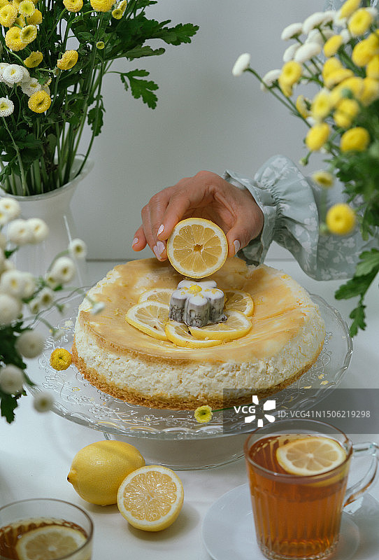 手拿柠檬片放在柠檬芝士蛋糕上的女人，美国北卡罗来纳州夏洛特图片素材