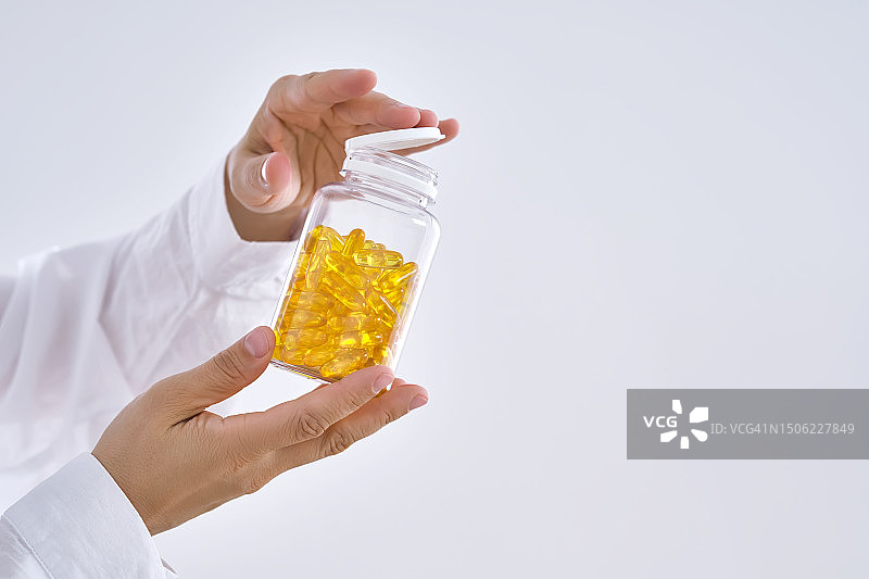 手持欧米茄3胶囊罐子的特写图片素材