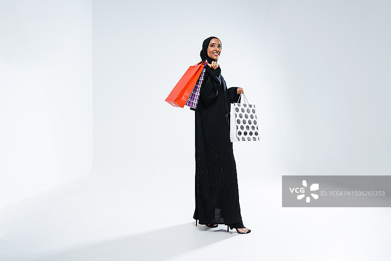 站在白色背景前的穿着黑色连衣裙的女人，阿拉伯联合酋长国图片素材