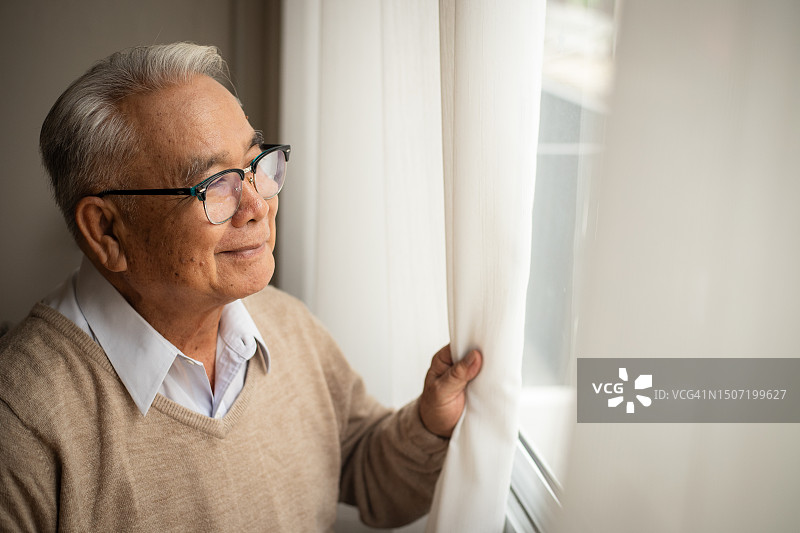 一位老人幸福地望着窗外。图片素材