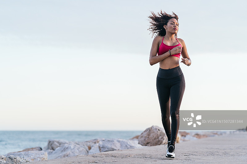 跑步的年轻西班牙裔卷发女子图片素材