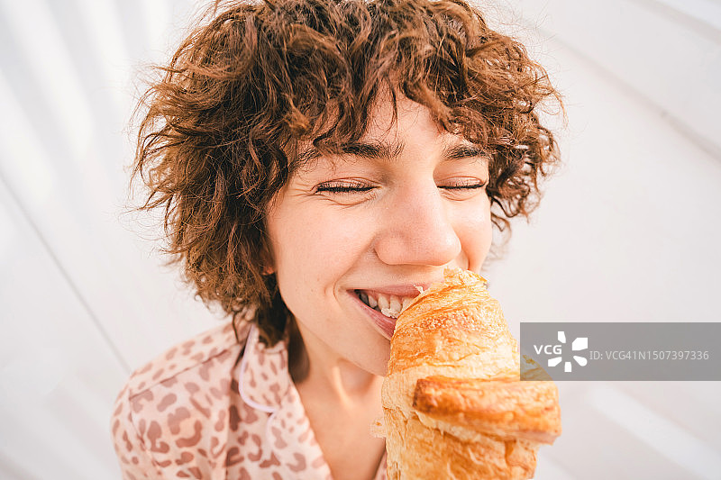 年轻法国女人吃着巨大羊角面包的有趣肖像图片素材