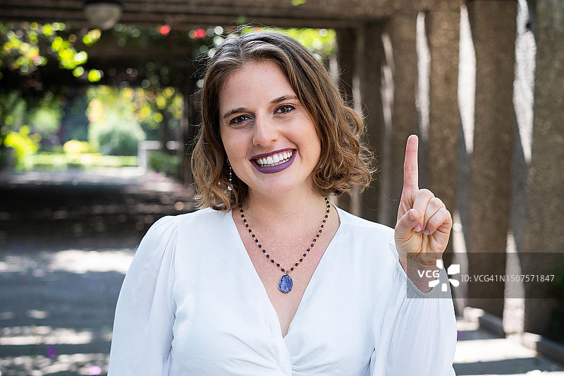 看着镜头并做出第一手势的笑容满面的女人图片素材