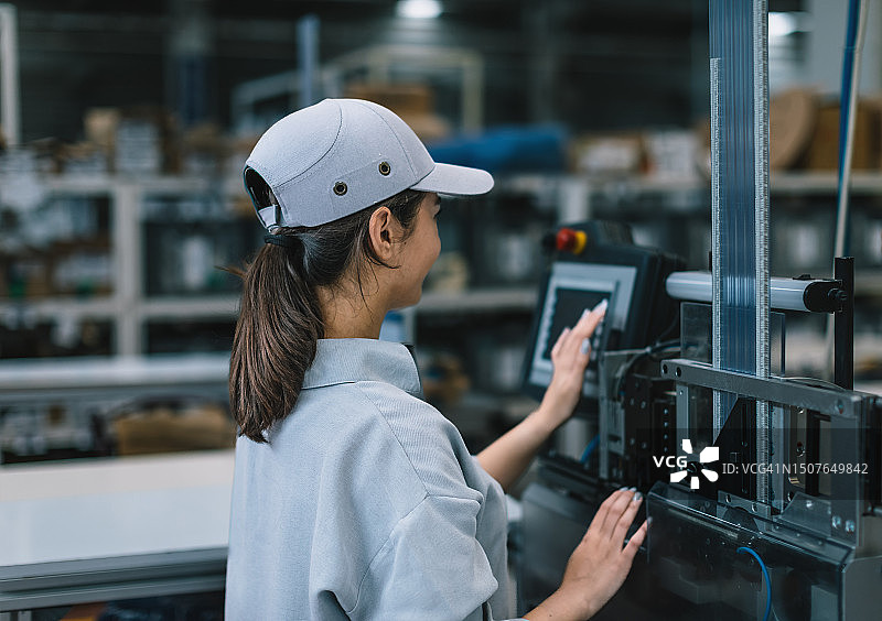 在机器旁工作的工业工厂女员工图片素材