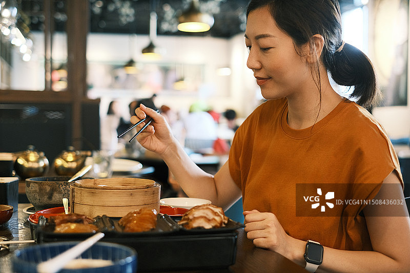 年轻的亚洲女人在餐厅享用传统北京烤鸭图片素材
