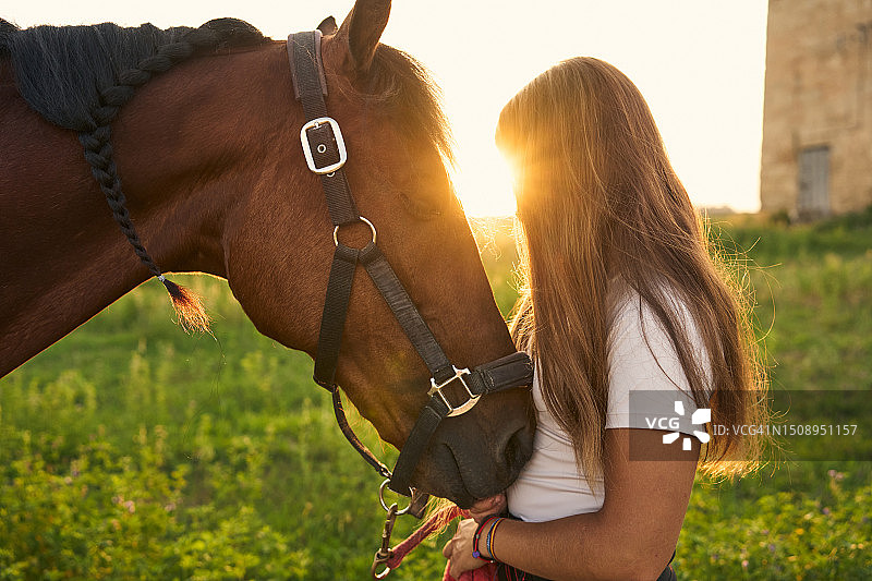 日落时分，女孩与马的侧面照图片素材