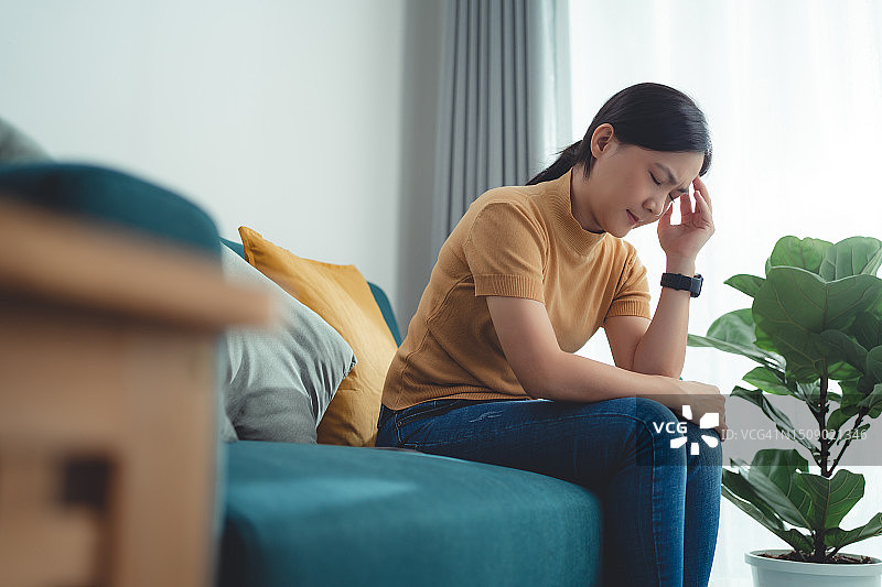 在家中客厅沙发上头痛的亚洲女性图片素材