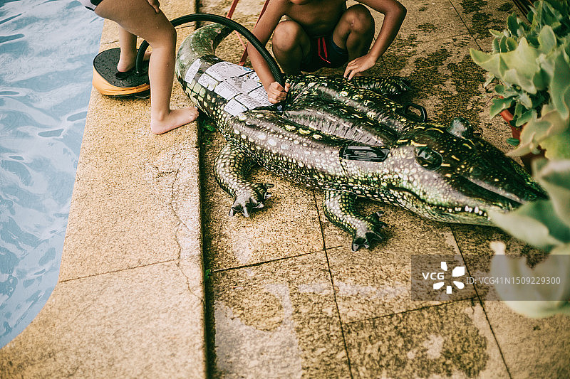 俯视拍摄的儿童在泳池边给鳄鱼充气图片素材