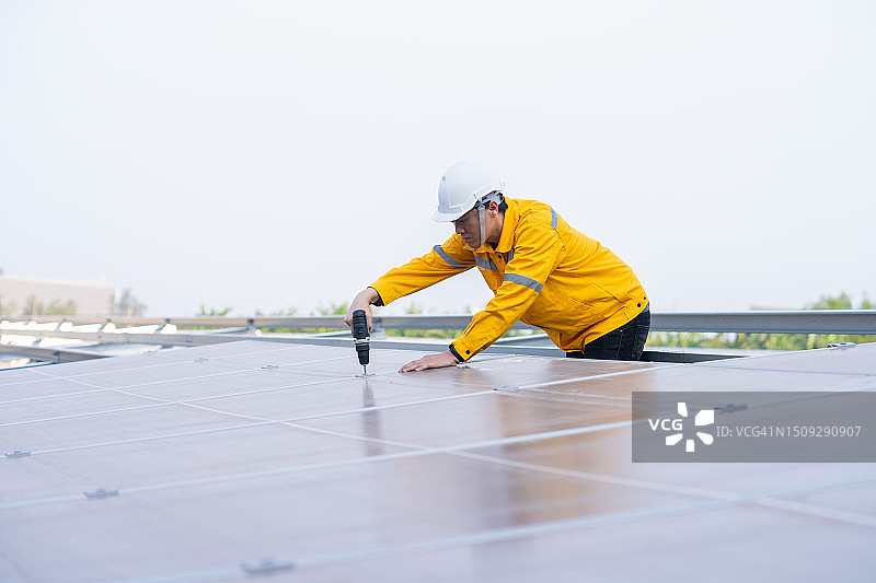 在太阳能电池板安装过程中使用钻头的工人图片素材