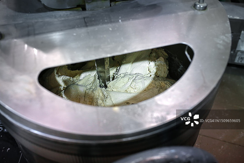 自动化揉面：食品生产中用于比萨面团揉捏的工业机器图片素材