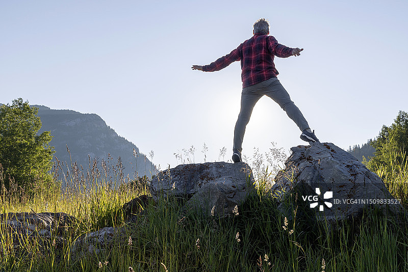 徒步旅行者在草甸的巨石顶端驻足图片素材