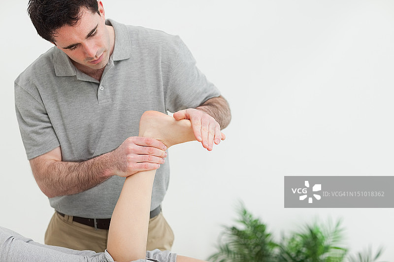 棕发治疗师为病人拉伸脚部图片素材