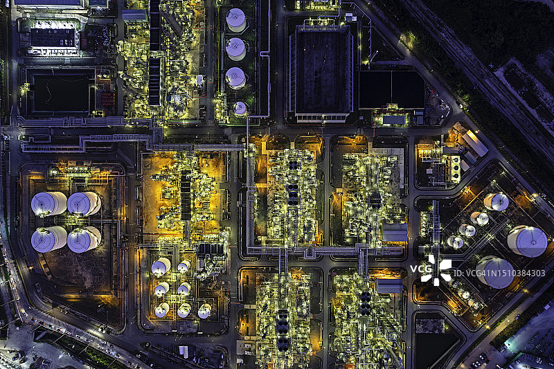 夜间炼油厂航拍俯视图，石油能源和石化工厂的塔罐与管道建设图片素材