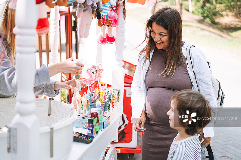 孕妇和小儿子在公园的商店帐篷里购物图片素材