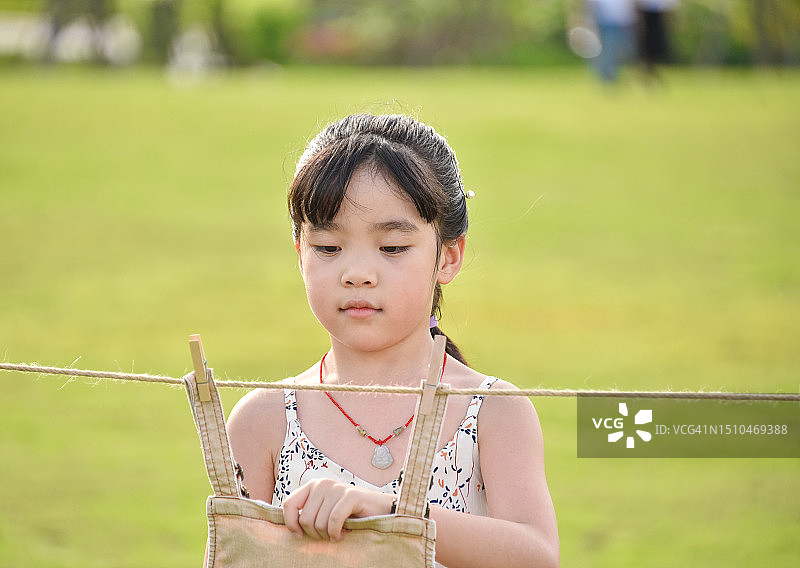 欢乐时光：在公园里晾衣服的亚洲小女孩（6-7岁），中国广东省江门市图片素材