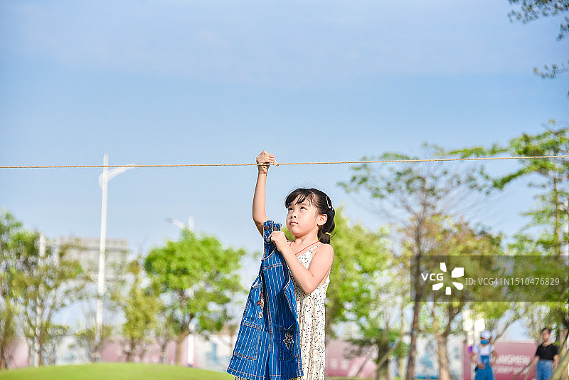 欢乐时光：在公园里晾衣服的亚洲小女孩（6-7岁），中国广东省江门市图片素材