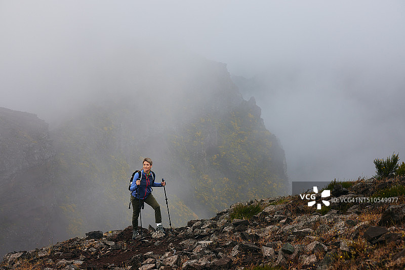 无忧无虑的女徒步旅行者在雾天站在山上图片素材