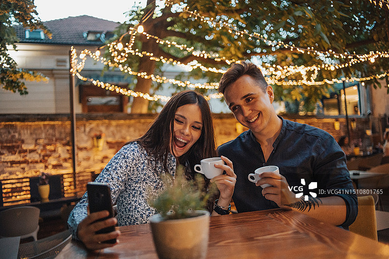 情侣在咖啡馆享受夜晚，美丽的灯笼营造出浪漫的氛围，他们看起来都很快乐和放松图片素材