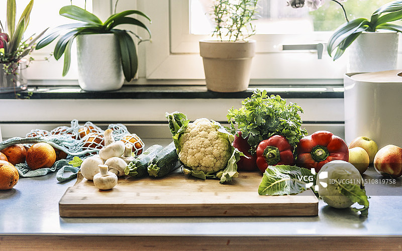 厨房餐桌，新鲜蔬菜与购物网袋图片素材