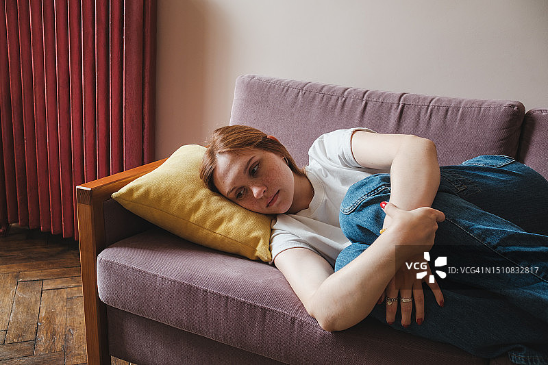 沮丧的少女在家抱膝坐在沙发上图片素材