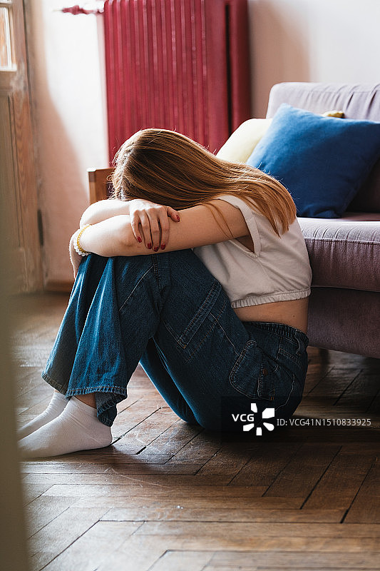 沮丧的抑郁少女用手捂着脸，独自在家哭泣图片素材