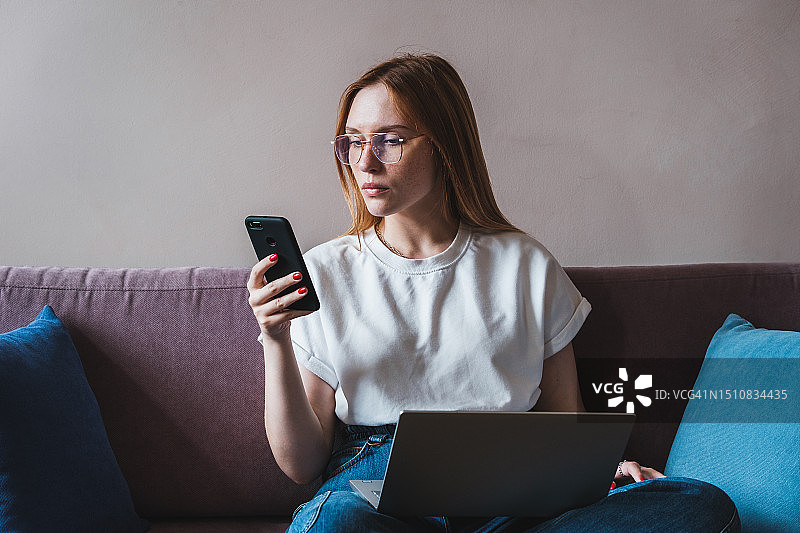 女学生在家使用手机和笔记本电脑在线学习时分心图片素材